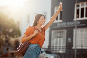 Image showing Waving for a taxi, waiting in the street for a ride outside. Smiling urban woman wants to travel downtown for work or fun with a cab. Lady gestures for transportation with confident arm raised.