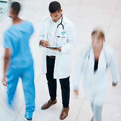 Image showing Busy hospital with doctor browsing on tablet for test results, patient records and medical research from above. Healthcare professional and expert working on treatment plan in a bustling clinic