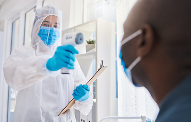 Image showing Healthcare worker, checking the temperature of male covid patient for safety against virus pandemic, wearing protective suit. Medical doctor in a hazmat suit, using a thermometer to prevent outbreak