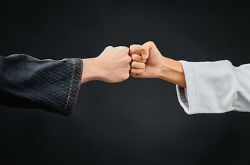 Image showing Teamwork, respect and discipline with hands fist bumping before a fight, match or mma competition. Closeup of two athletes greeting before combat sport and self defense against a black background