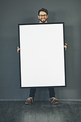 Image showing Man standing with a blank sign or portrait frame, showing copy space for advertising or marketing with dark background. Happy, smiling and intelligent guy holding big white poster or page copyspace