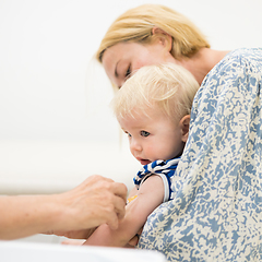 Image showing Child beeing vaccinated by pediatrician in presence of his mother. Preventive vaccination against Diphtheria, whooping cough, tetanus, hepatitis, haemophilus influenzae, pneumococcus, poliomyelitis