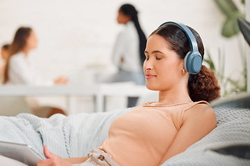 Image showing Rest, relaxation and break with a modern and creative design professional listening to music with wireless headphones on a beanbag chair. Young business woman resting in her office for mental health