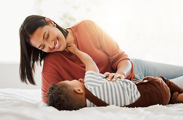 Image showing Happy, love and family time with a mother and son being playful and bonding on a bed at home. Parent playing with her child, smiling and enjoying motherhood. Single mom embracing her son.