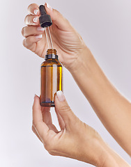 Image showing Skincare serum, essential oil and cosmetic product in woman hand for perfect, smooth skin or reduce wrinkles isolated on studio background. Closeup hands using body care or anti aging liquid drop