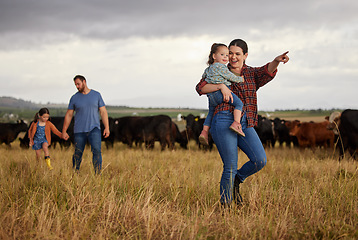 Image showing Happy family bonding on a cattle farm, walking and looking at animals, relaxing outdoors together. Young parents showing child girls how to care for livestock and having fun on exploring nature walk