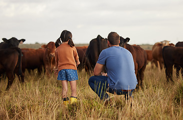 Image showing Father and daughter bonding at a cattle farm, having fun and learning how to care for livestock. Parent and child enjoying outdoors in nature, looking at cows and talking. Farmer showing kid animals