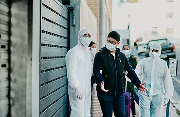 Image showing Man breaking covid regulation getting taken away or arrested by healthcare workers wearing hazmat protective suits. Male removed for not following the rules or restrictions of coronavirus pandemic