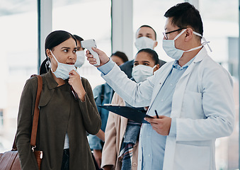 Image showing Travel medical healthcare worker testing covid temperature at airport using infrared thermometer. Professional doctor doing a coronavirus check up on a woman at an office entrance