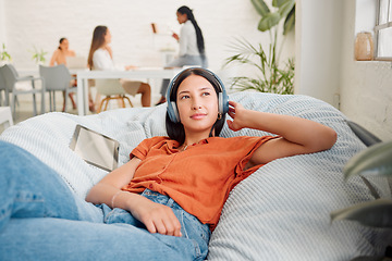 Image showing Creative wearing headphones, listening to music and relaxing with zen songs or podcast to help with thinking, planning and inspiration. Motivated, inspired and ambitous woman lying on office bean bag