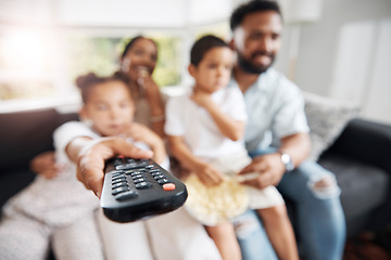 Image showing Closeup of remote control with family watching tv in their living room together. Parents and kids relaxing on the sofa enjoying a movie, series or cartoons in the lounge at home while bonding