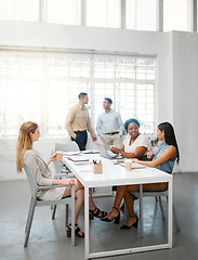 Image showing Corporate, professional and serious business people talking in meeting, discussing and making conversation in a modern office together at work. DIverse, young and concentrated colleagues planning