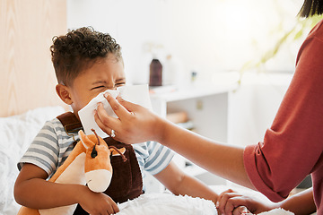 Image showing Flu, sick or cold child with parent sneezing, blowing and wiping runny nose while ill with covid virus, sinus and allergy symptoms in bed at home. Mother caring for stuffy and congested little son