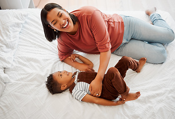 Image showing Mother playing, bonding and laughing with her son playful, fun and funny moments together on the bed at home. Parenting and enjoying quality, happy single mom and her child in kids bedroom.