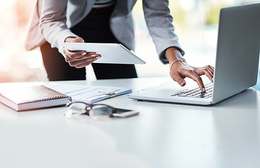 Image showing Reading, sending or checking an email or report while at work in at a professional desk. Hands typing on a laptop keyboard and holding a tablet with a business woman working in her corporate office.