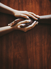 Image showing Support, love and a couple holding hands at a table from above with copyspace. Interracial friends praying, consoling and showing care at therapy or after bad news. Unity and affection after grief.