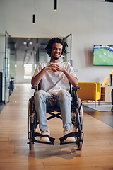 Image showing A businessman in a wheelchair occupies a hallway within a modern startup coworking center, embodying inclusivity and determination in the business environment