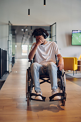 Image showing A sad businessman in a wheelchair occupies a hallway within a modern startup coworking center, embodying inclusivity and determination in the business environment