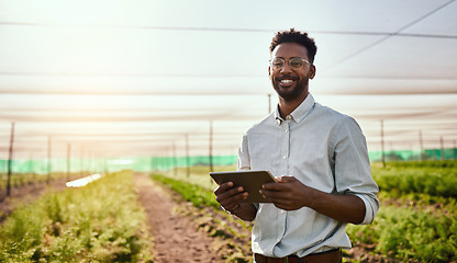 Image showing Young African male farmer working on healthy agriculture development strategy on his digital tablet. Smiling field worker outdoors on organic farming and growth sustainability check up