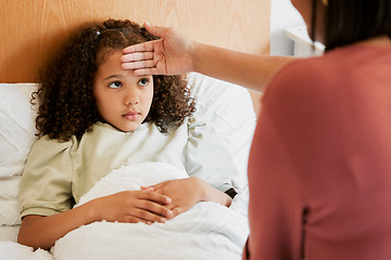 Image showing Concerned, anxious and unwell girl suffering with cold or flu while her mother checks her temperature at home. Worried parent caring for her sick child, feeling for fever while worrying about corona