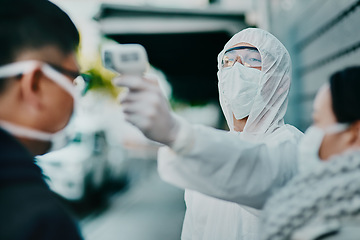 Image showing Travel restrictions, airport or border testing patient temperature outside with a thermometer. Medical safety officer doing a covid check on a man at the entrance to prevent the spread of the virus.