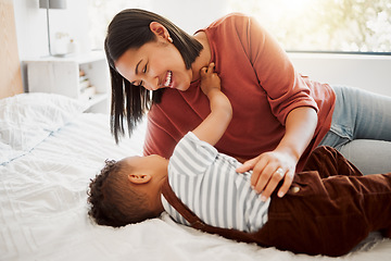 Image showing Happy, loving family with a mother and son being playful and bonding on a bed at home. Smiling parent playing with her child, laughing and enjoying motherhood. Single parent embracing her son