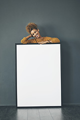 Image showing A beautiful confident woman holding a blank whiteboard or billboard sign with copy space. Happy and attractive female with a smile standing behind a banner. Young lady advertising with a poster