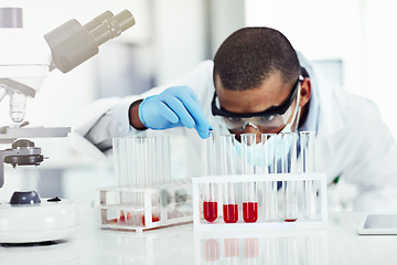 Image showing Smart looking scientist working with blood sample, DNA testing or virus research in a lab. Black male science or biology expert analyzing test tube for disease or medical innovation in a laboratory