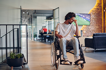 Image showing A sad businessman in a wheelchair occupies a hallway within a modern startup coworking center, embodying inclusivity and determination in the business environment