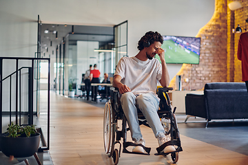 Image showing A sad businessman in a wheelchair occupies a hallway within a modern startup coworking center, embodying inclusivity and determination in the business environment