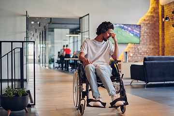 Image showing A sad businessman in a wheelchair occupies a hallway within a modern startup coworking center, embodying inclusivity and determination in the business environment