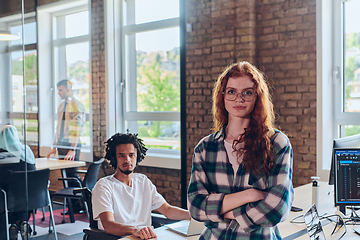 Image showing A portrait of a young businesswoman with modern orange hair captures her poised presence in a hallway of a contemporary startup coworking center, embodying individuality and professional confidence.