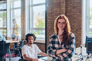 Image showing A portrait of a young businesswoman with modern orange hair captures her poised presence in a hallway of a contemporary startup coworking center, embodying individuality and professional confidence.