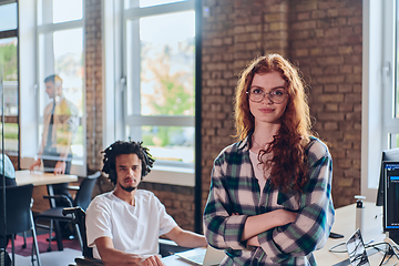 Image showing A portrait of a young businesswoman with modern orange hair captures her poised presence in a hallway of a contemporary startup coworking center, embodying individuality and professional confidence.