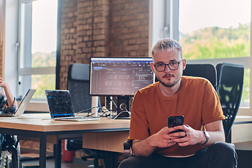 Image showing A modern businessman takes a relaxing break from work, using his smartphone to unwind and recharge during his pause