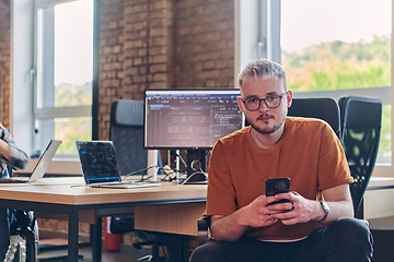 Image showing A modern businessman takes a relaxing break from work, using his smartphone to unwind and recharge during his pause