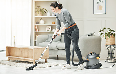 Image showing Vacuuming, cleaning and housework done by a mother, house wife or girlfriend using a vacuum cleaner. Stay at home mom, maid or housekeeper doing household chores and tidying in a modern living room