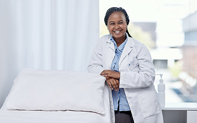Image showing Happy doctor leaning on a hospital bed smiling, standing and ready to serve, assist and help you get healthy. Cheerful, friendly and young medical professional inside an emergency healthcare facility