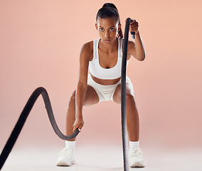 Image showing Fit woman doing cardio workout with ropes, exercising for fitness training and looking sporty while posing against a pink studio background. Active and young female athlete doing exercise routine