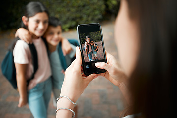 Image showing Children first day of school and mother taking photos with a phone of her cute kids. Closeup of screen picture of brother and sister embracing while posing for their mom outside in the morning