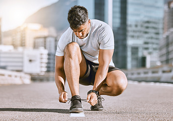 Image showing Wellness and fitness runner ties shoes lace before running in a city street during summer. Healthy man athlete prepare sneaker for a comfortable fit for a sport exercise, training or marathon workout