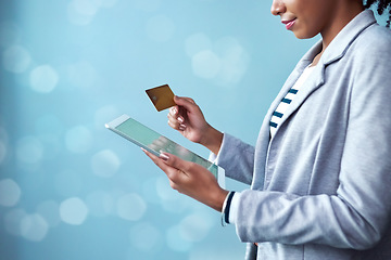 Image showing Credit card for online banking, shopping and buying on tablet while standing alone isolated on blue copy space. African female paying for purchase with fintech technology on blue bokeh background