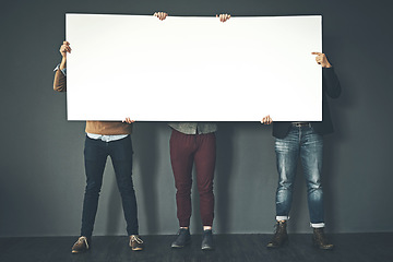 Image showing Group of businesspeople holding up a copyspace sign voicing their opinion at work with a grey background. People with blank poster advertising, marketing and express or convey important messages