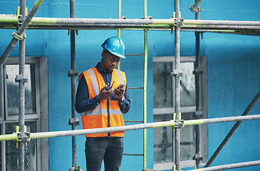 Image showing Male construction worker working checking a digital building plan on a phone. Busy urban development builder looking at buildings planning data to give industry information on a two way radio