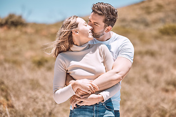 Image showing Hugging, embracing and in love young couple spending a romantic summer day in nature together. Happy partners on a getaway kissing, smiling and relaxing outdoors enjoying and loving the sunshine