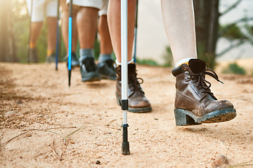 Image showing . Group of hikers hiking with walking sticks on a trail outdoors in nature for fitness. Fit, active and sporty people on an adventure. Adult friends taking a stroll for exercise and health.