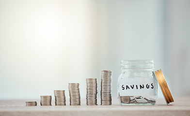 Image showing Finance, budget and saving money or coins by depositing currency, cash and pennies in a glass jar on copy space background. Closeup of piled, stacked and heaped cents for planning or future investing