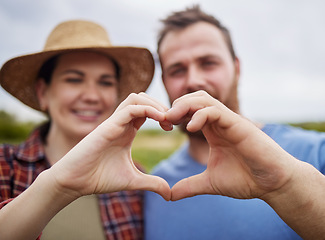 Image showing Farmer couple support sustainability by making a love heart sign with their hands outdoors on an organic farm. Happy and carefree activists with a passion for sustainable and organic farming