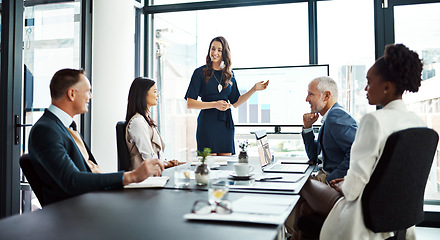 Image showing Business woman speaker in an investment meeting with financial data on a boardroom screen. International executive team listening to a presentation. Finance worker talking at a partnership proposal