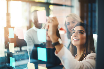 Image showing Team leader planning and writing on sticky notes while showing innovation, sharing a vision and ideas. Diverse group of creative office business people meeting together to market new startup company